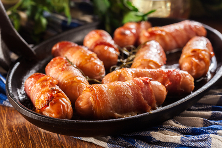 Pigs in blankets. Mini sausages wrapped in smoked bacon in baking dishの写真素材