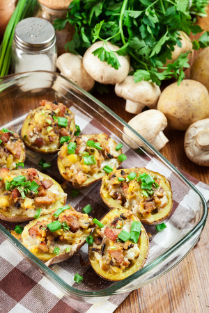 Baked potatoes in jacket stuffed with bacon, mushrooms and cheese. Dish served in baking dishの写真素材