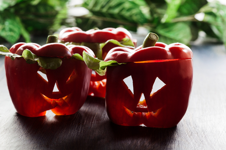 Halloween food. Red sweet bell peppers with cut out facesの写真素材