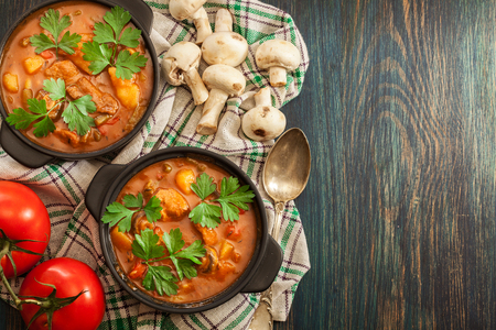 Stew soup with meat, potatoes, mushrooms and red pepper in bowl. Top viewの写真素材