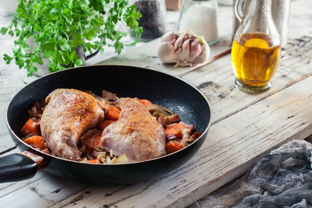 Fried rabbit legs on frying pan with vegetables and herbsの写真素材