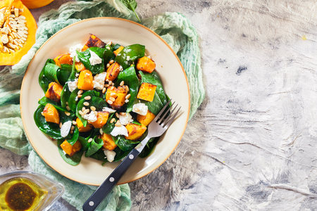 Roasted pumpkin salad with spinach, feta and pine nuts. Autumn dish