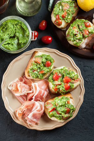 Bruschetta with fresh pesto, mozzarella and cherry tomatoes on a plateの写真素材