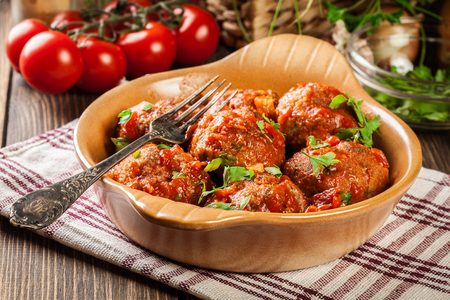 Pork meatballs with spicy tomato sauce in dish on wooden tableの写真素材