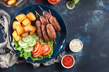Grilled shish kebab served with fried potatoes and vegetable salad