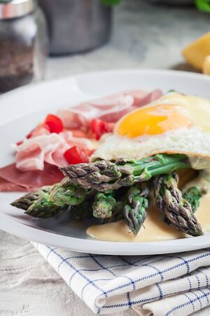 Green asparagus with prosciutto ham, fried egg and hollandaise sauce. Spring dishの写真素材