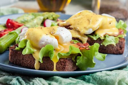 Sandwiches with bacon and poached egg. Served with hollandaise sauce and asparagus