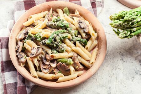 Penne pasta with green asparagus, prosciutto and mushroom in cheese sauceの写真素材