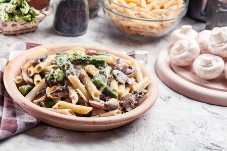 Penne pasta with green asparagus, prosciutto and mushroom in cheese sauceの写真素材