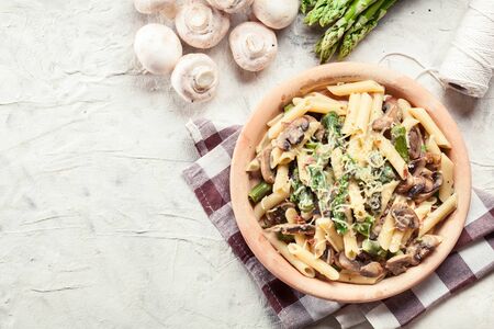 Penne pasta with green asparagus, prosciutto and mushroom in cheese sauceの写真素材