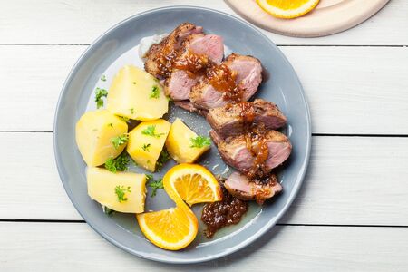 Roast duck breast with orange sauce served with potatoの写真素材