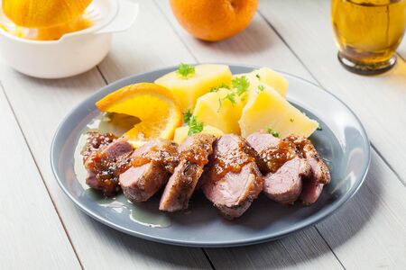 Roast duck breast with orange sauce served with potatoの写真素材