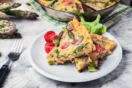 Portion of frittata. Made of eggs, asparagus and cherry tomatoes. Italian cuisineの写真素材