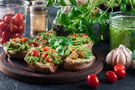 Bruschetta with fresh pesto, mozzarella and cherry tomatoes on cutting boardの写真素材