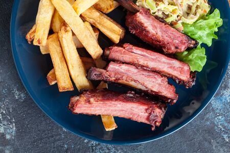 Spicy barbecued pork ribs served with french fries and BBQ sauceの写真素材