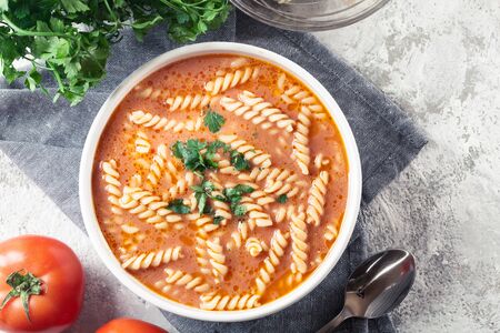 Tomato soup with fusilli pasta in the bowl on a bright backgroundの写真素材