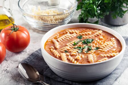 Tomato soup with fusilli pasta in the bowl on a bright backgroundの写真素材