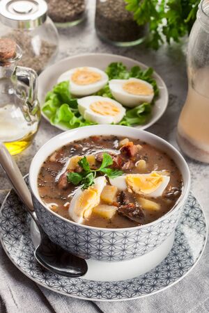 The sour soup made of rye flour with mushrooms and bacon served with eggsの写真素材