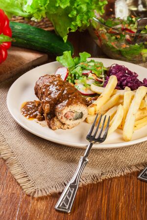 Pork roulade with french fries with salad on a plateの写真素材