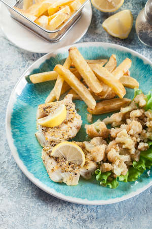 Steamed cod fish with french fries and boiled cauliflower on a plate