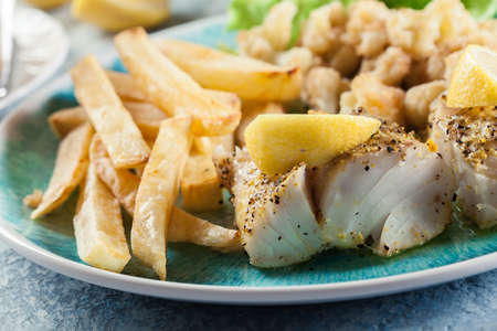 Steamed cod fish with french fries and boiled cauliflower on a plate