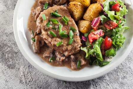 Pork loin chop with mushroom sauce and baked potatoes. Delicious dishの写真素材