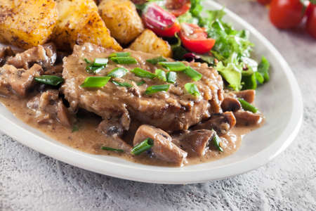 Pork loin chop with mushroom sauce and baked potatoes. Delicious dishの写真素材