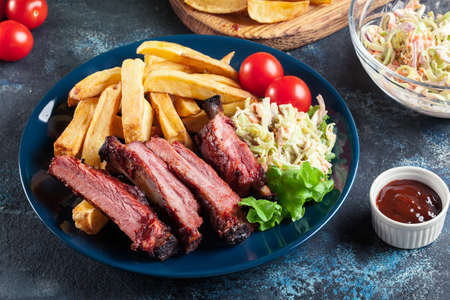Spicy barbecued pork ribs served with french fries and BBQ sauceの写真素材