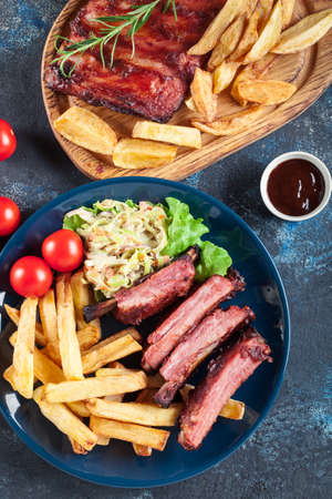 Spicy barbecued pork ribs served with french fries and BBQ sauceの写真素材