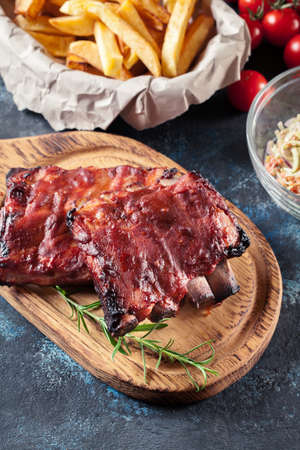 Spicy barbecued pork ribs served with BBQ sauce on chopping boardの写真素材