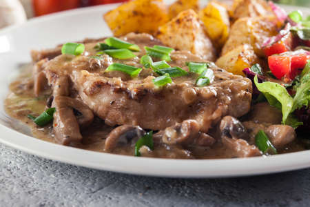 Pork loin chop with mushroom sauce and baked potatoes. Delicious dishの写真素材