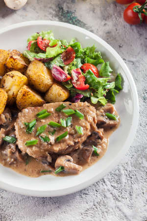 Pork loin chop with mushroom sauce and baked potatoes. Delicious dishの写真素材
