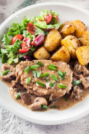 Pork loin chop with mushroom sauce and baked potatoes. Delicious dishの写真素材