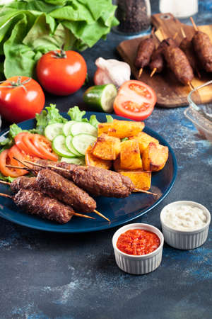 Grilled shish kebab served with fried potatoes and vegetable saladの写真素材