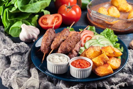 Grilled shish kebab served with fried potatoes and vegetable saladの写真素材