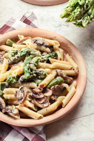 Penne pasta with green asparagus, prosciutto and mushroom in cheese sauceの写真素材