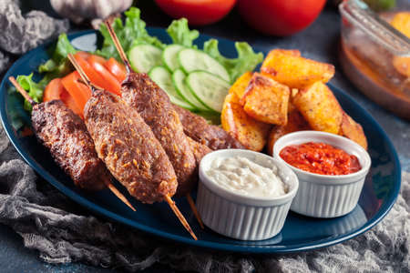 Grilled shish kebab served with fried potatoes and vegetable saladの写真素材