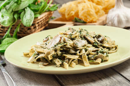 Tagliatelle pasta with spinach and mushrooms on a plate. Vegetarian food.の写真素材
