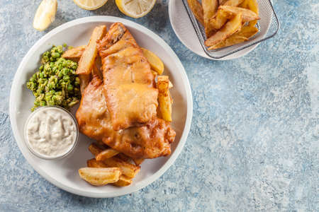 Traditional fish in beer batter and chips with green pea and tartar sauceの写真素材