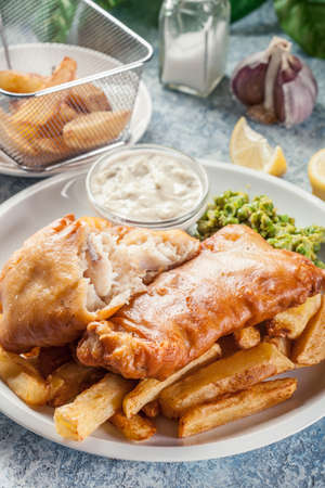 Traditional fish in beer batter and chips with green pea and tartar sauceの写真素材