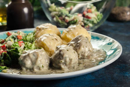 Meatballs with creamy and cheese gravy served with mashed potatoes balls and saladの写真素材