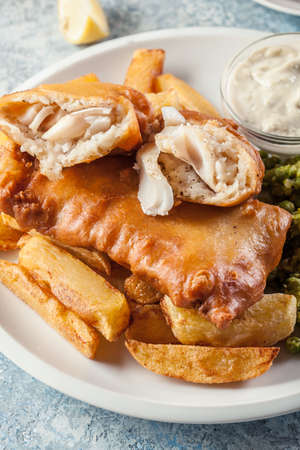 Traditional fish in beer batter and chips with green pea and tartar sauceの写真素材