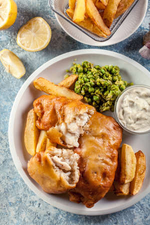Traditional fish in beer batter and chips with green pea and tartar sauceの写真素材