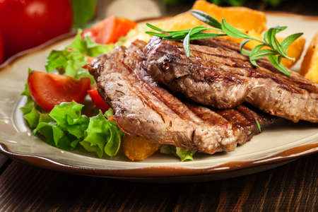 Succulent portions of grilled fillet mignon served with baked potatoes on a plateの写真素材