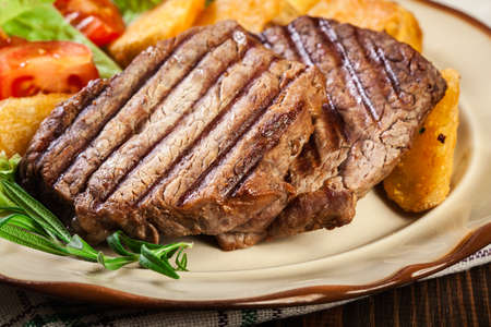 Succulent portions of grilled fillet mignon served with baked potatoes on a plateの写真素材