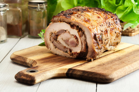 Roasted pork roll stuffed with other meat and dried tomatoes on cutting boardの写真素材