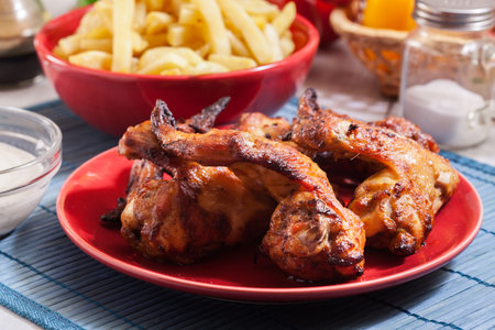 Tasty baked chicken wings on a plate served with french friesの写真素材