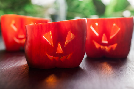 Halloween food. Red sweet bell peppers with cut out facesの写真素材