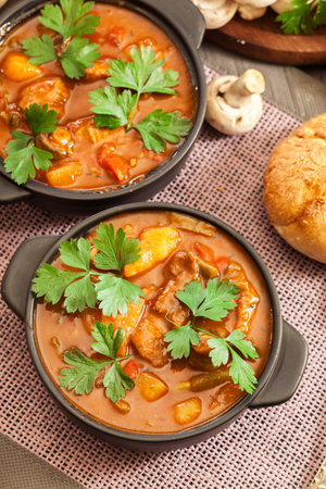 Stew soup with meat, potatoes, mushrooms and red pepper in bowlの写真素材