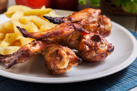 Tasty baked chicken wings on a plate served with french friesの写真素材